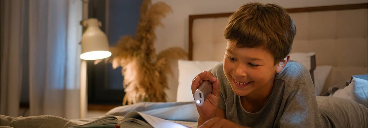 enfant entrain de lire un livre dans chambre en souriant