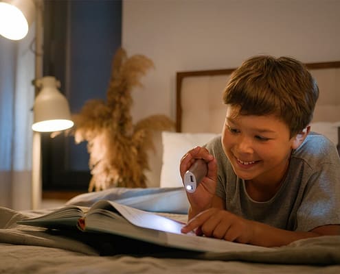 enfant entrain de lire un livre dans chambre en souriant